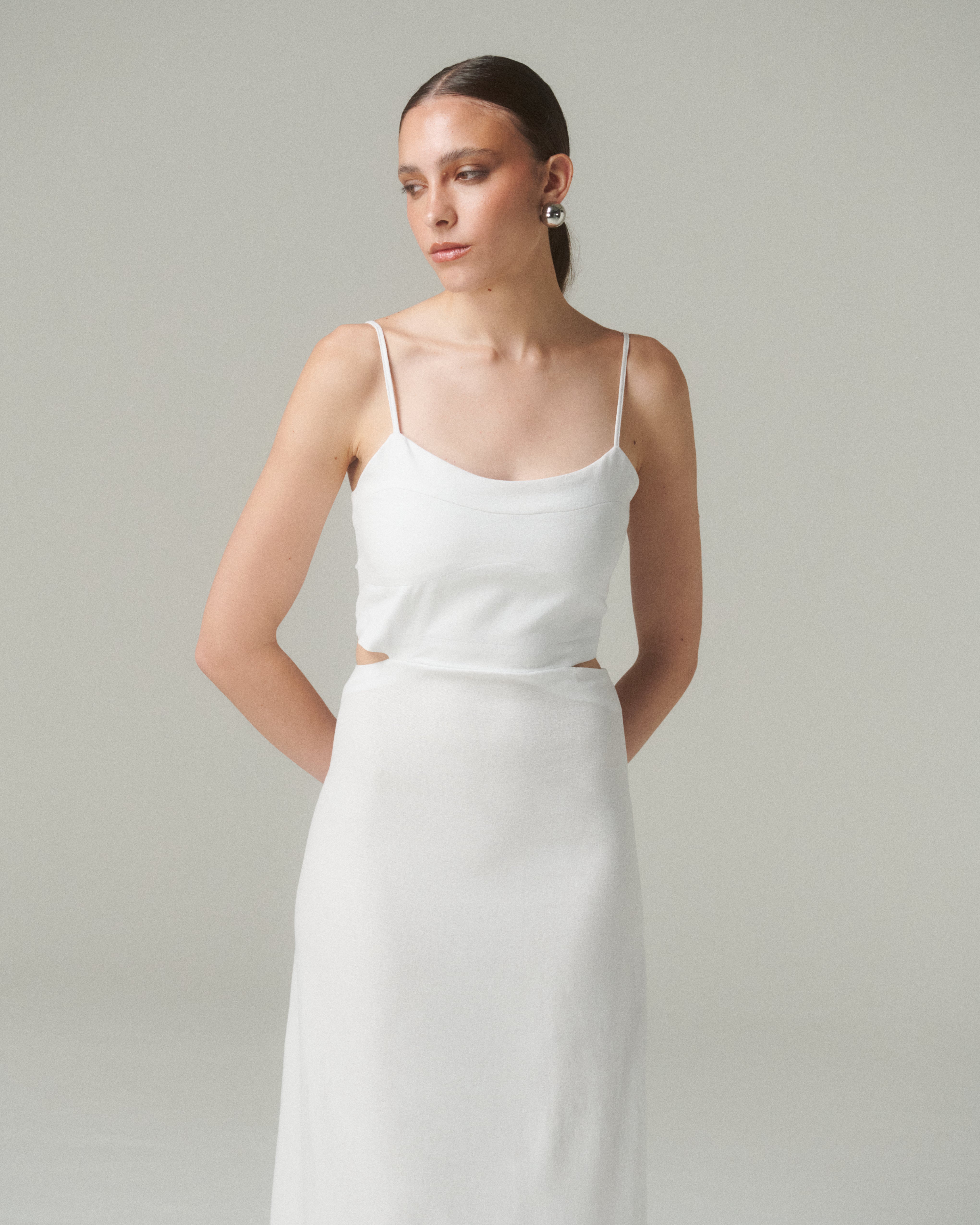 Modelo luciendo el Vestido Moa Blanco con tirantes finos y diseño elegante en fondo neutral.