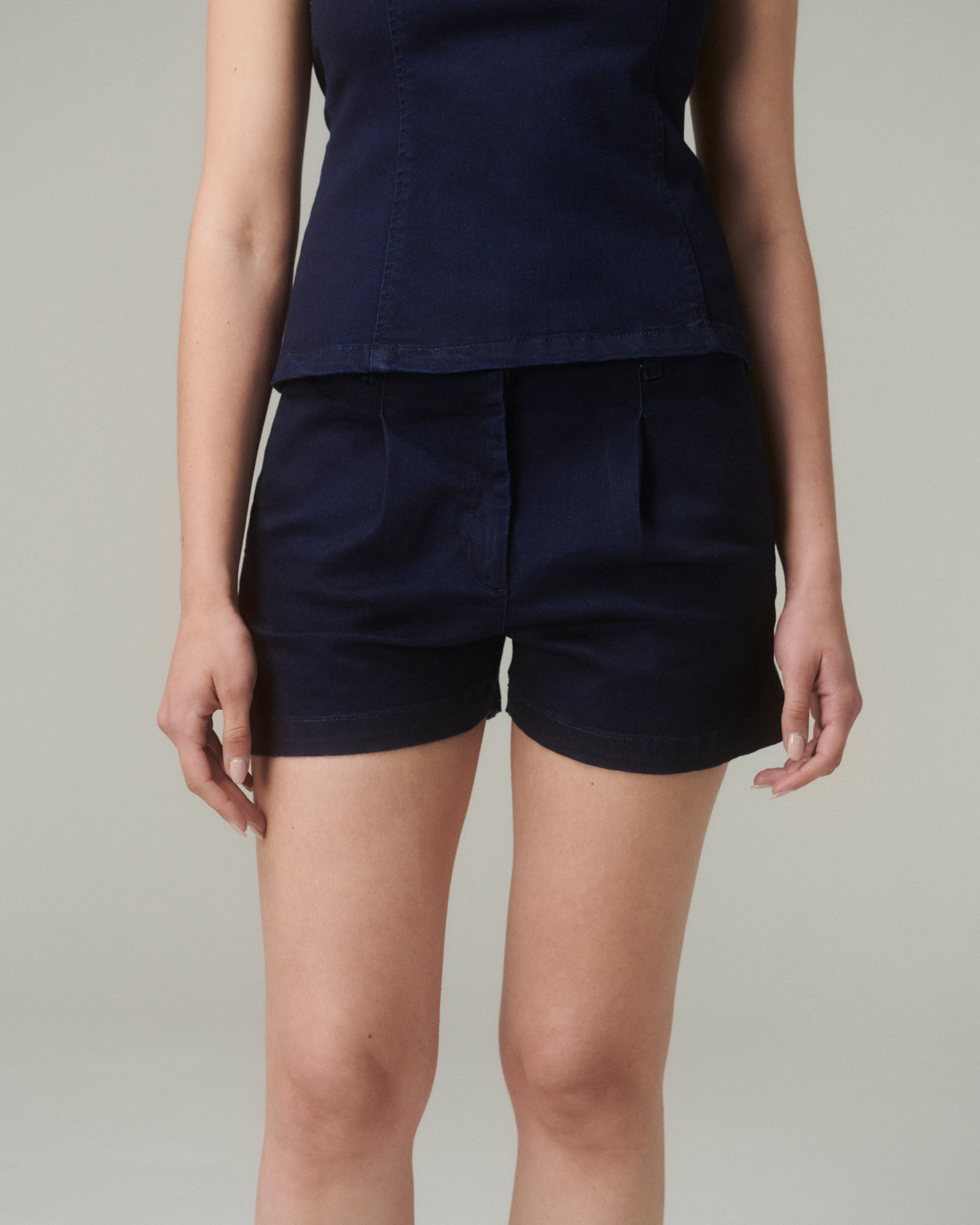 Close up del Short Iona Denim, mostrando tiro medio, pinzas frontales y pretina recta con botón dorado.