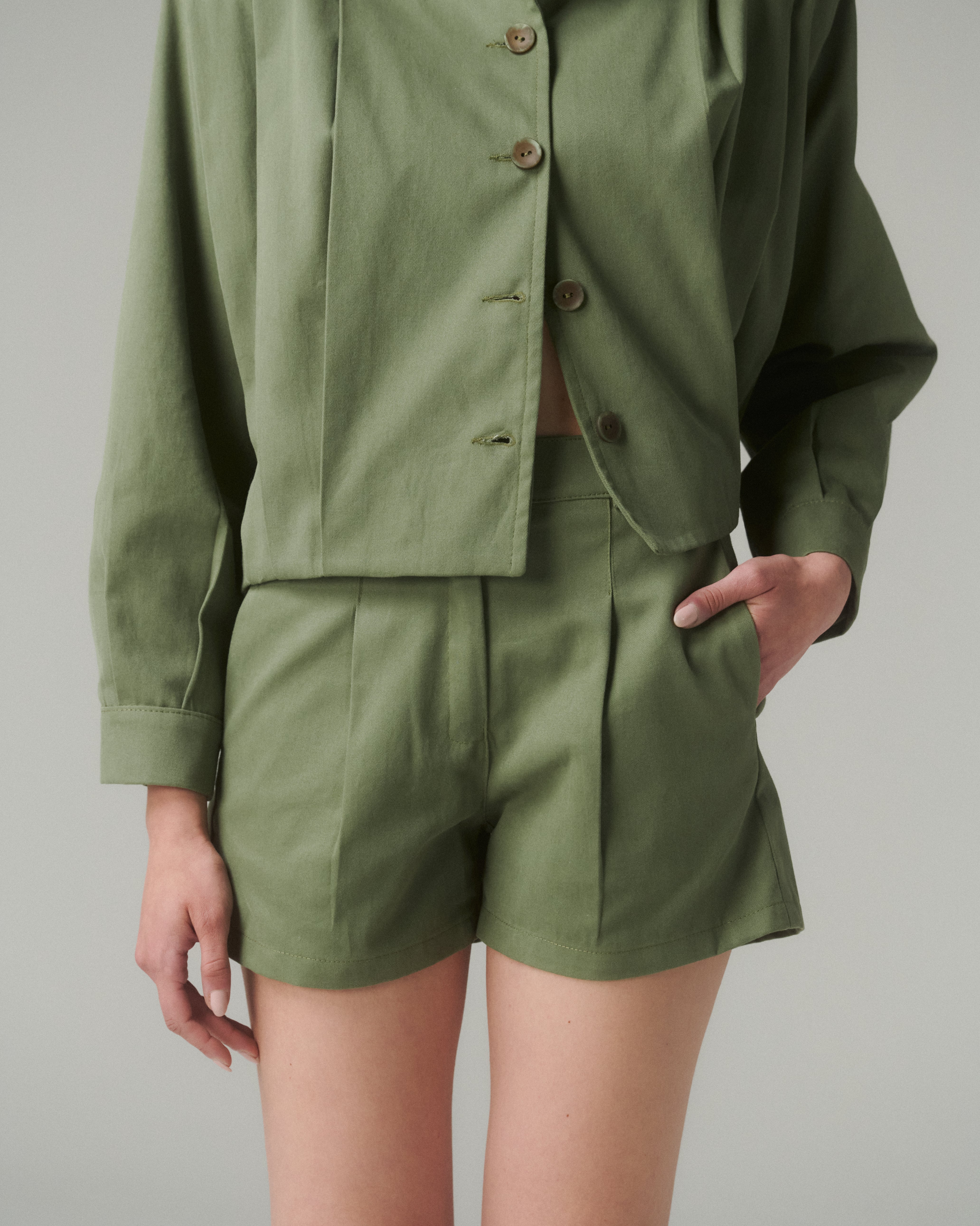 Primer plano frontal del Short Lua Verde, mostrando tiro medio, pinzas frontales y pretina recta con broche interior.