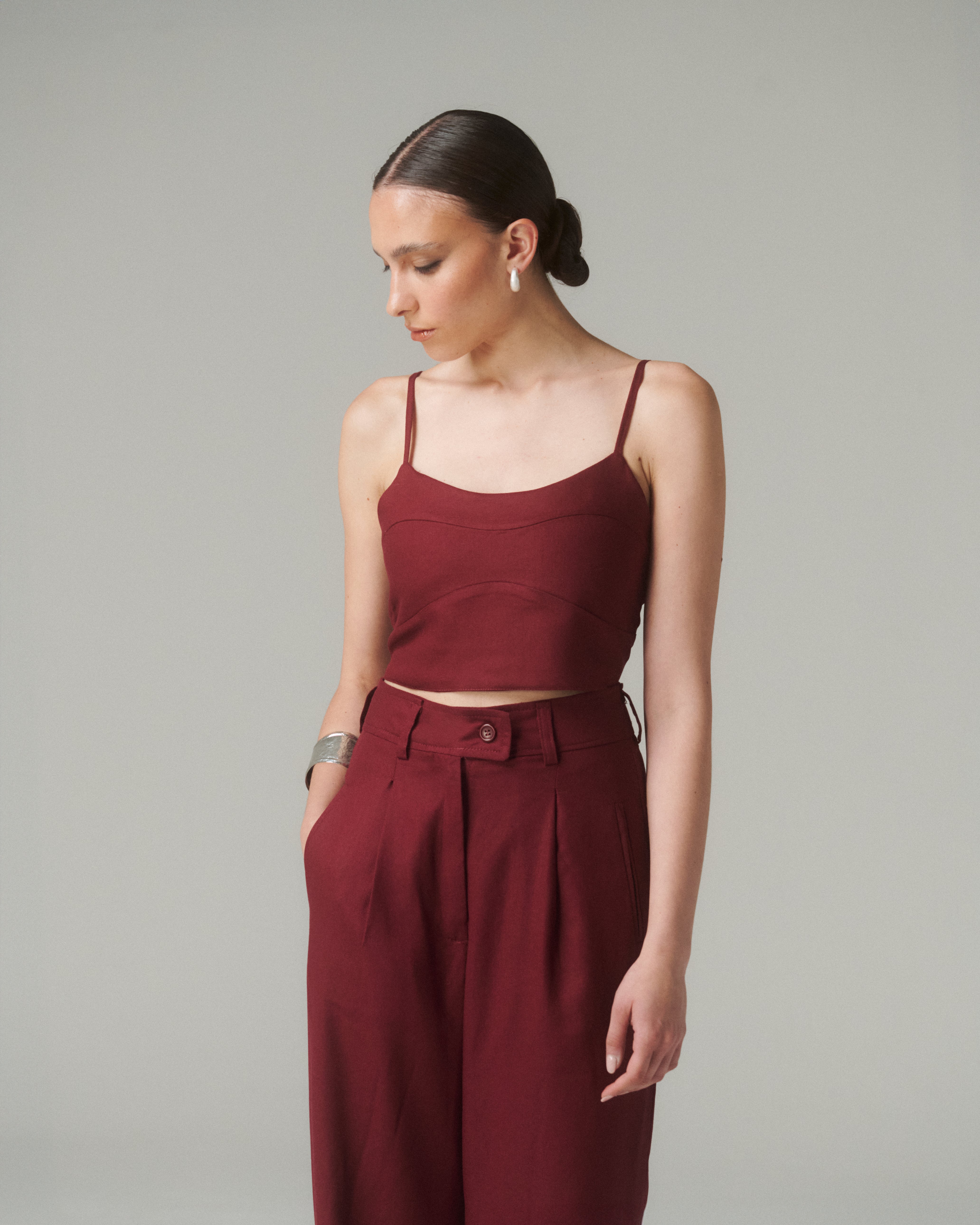 Blusa Nina Burdeo, elegante blusa burgundy de tirantes finos con diseño contemporáneo y lazo ajustable en la espalda.