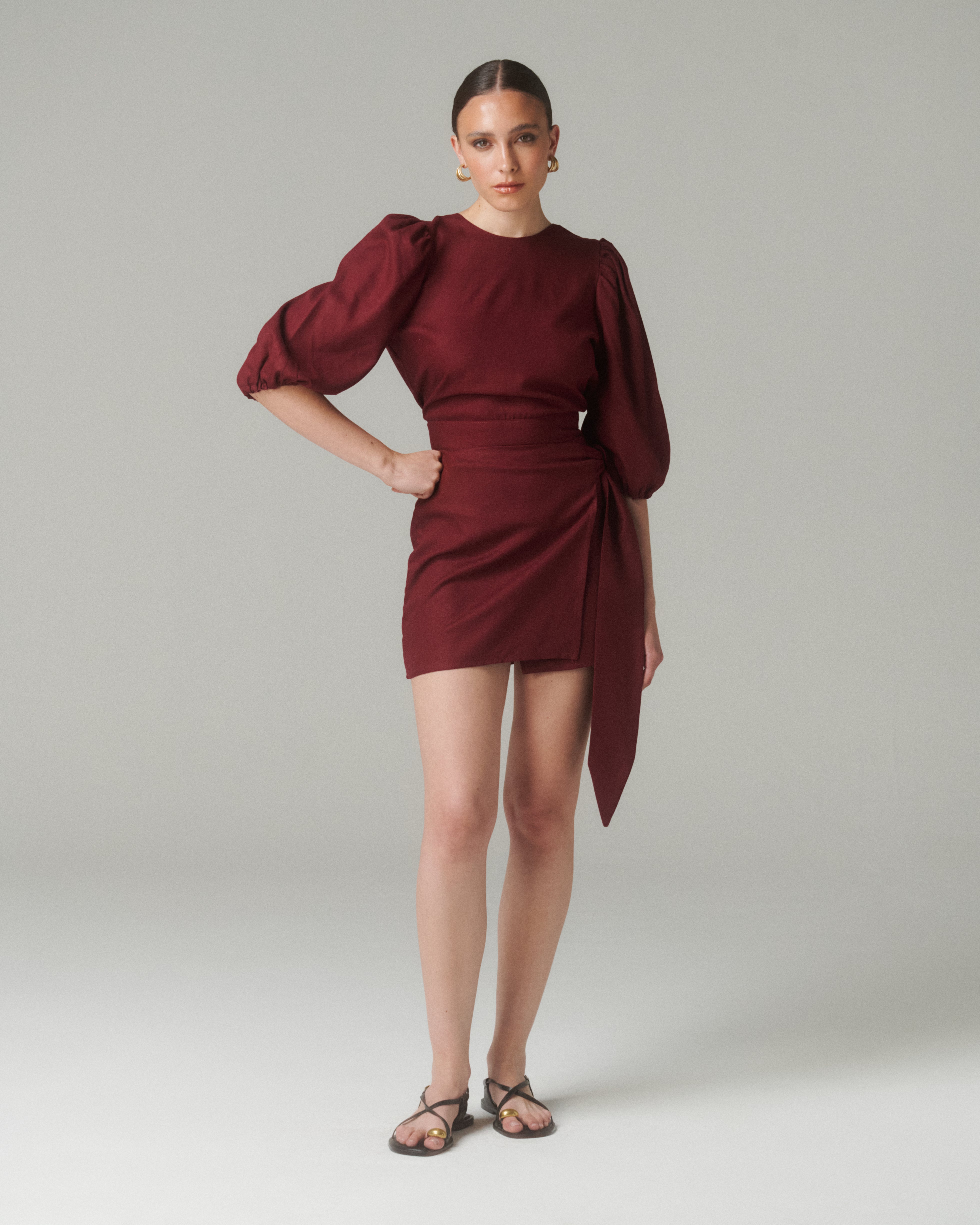 Vista de frente de la Blusa Aura Burdeo, modelo con brazo posado en la cadera, destacando el cuello medio y las mangas abullonadas ¾.