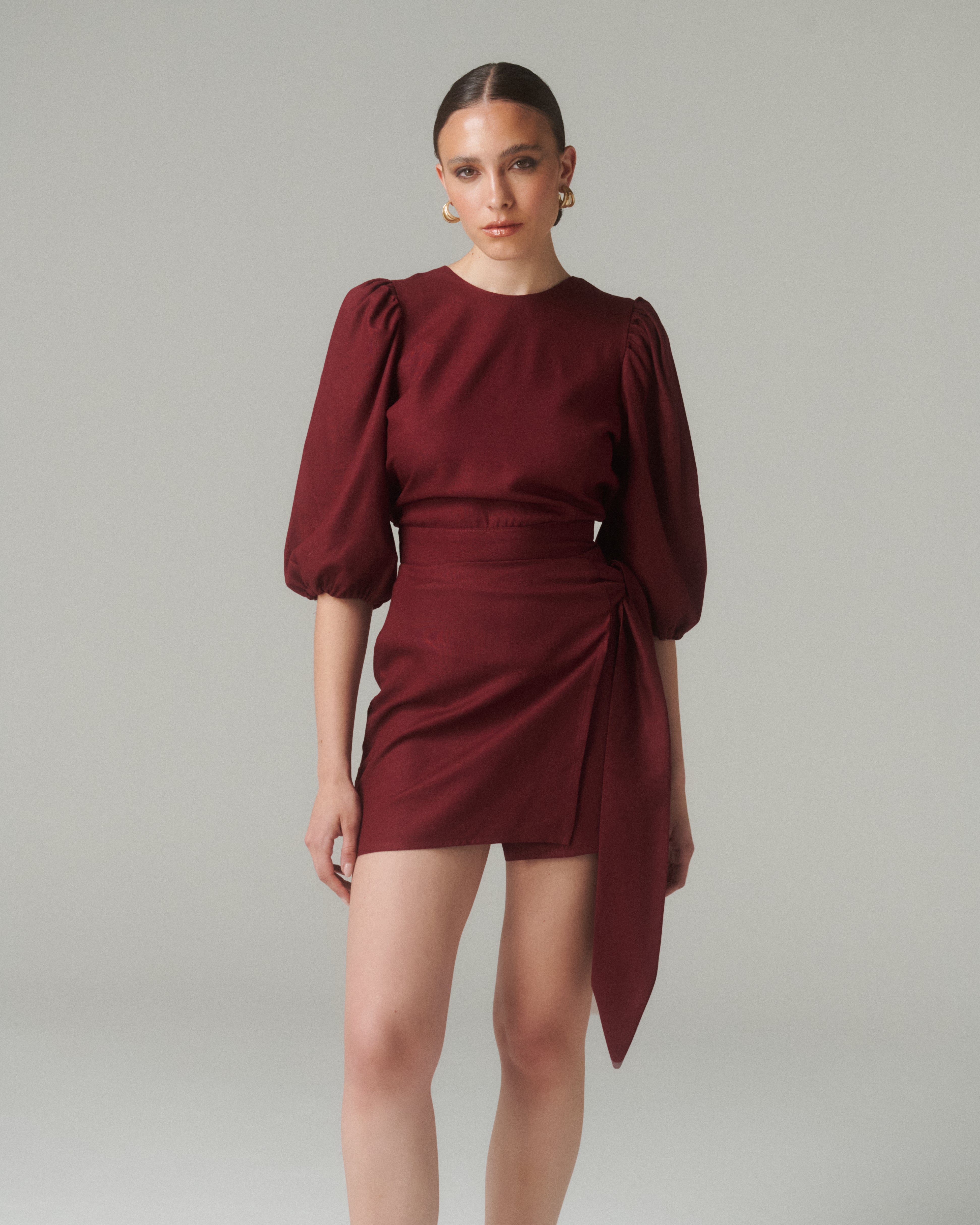 Vista de frente de medio cuerpo de la Blusa Aura Burdeo, resaltando el ajuste en la cintura y el diseño elegante del torso.