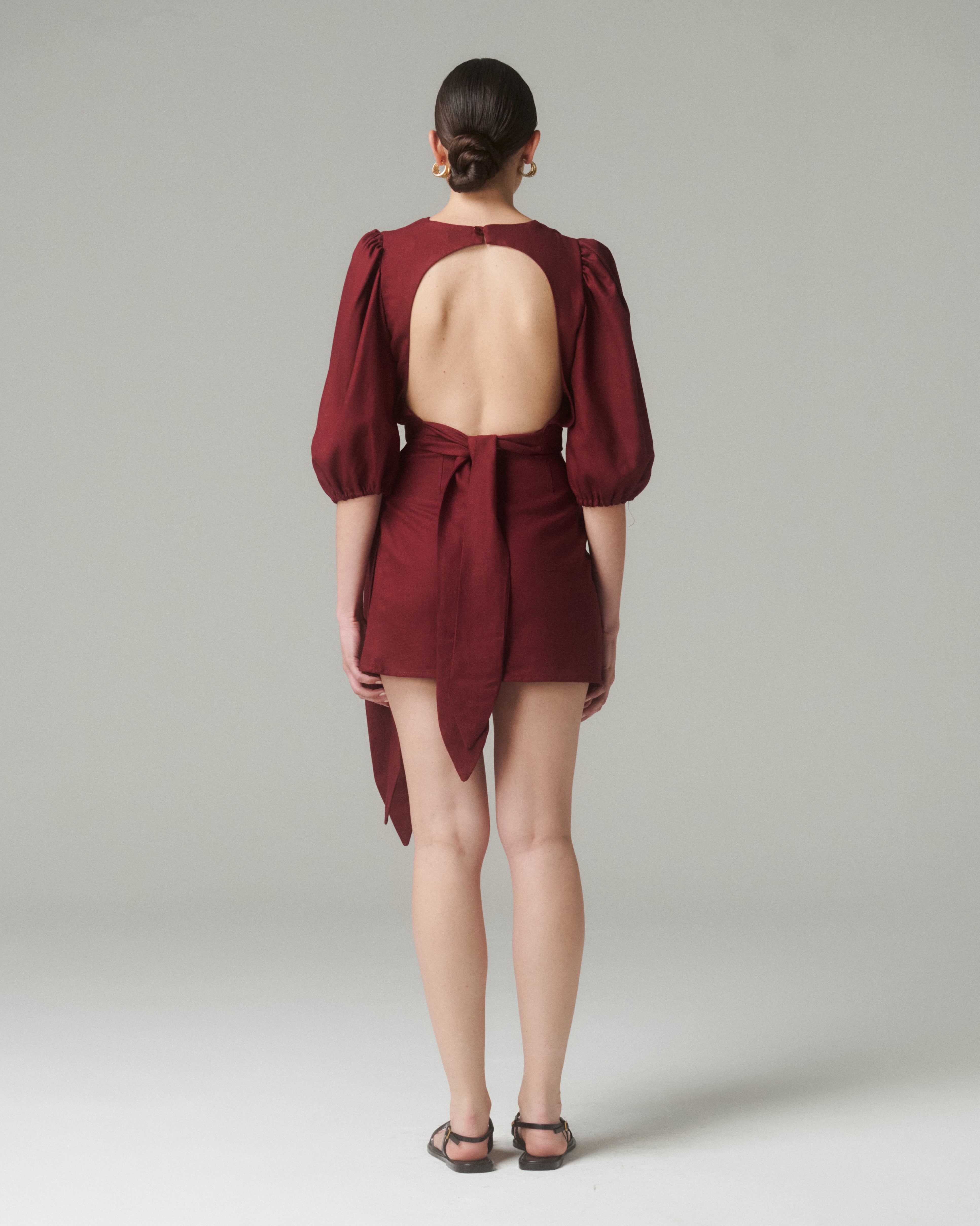 Vista trasera de la Blusa Aura Burdeo, mostrando el corte en la espalda y el lazo ajustable que define la silueta.