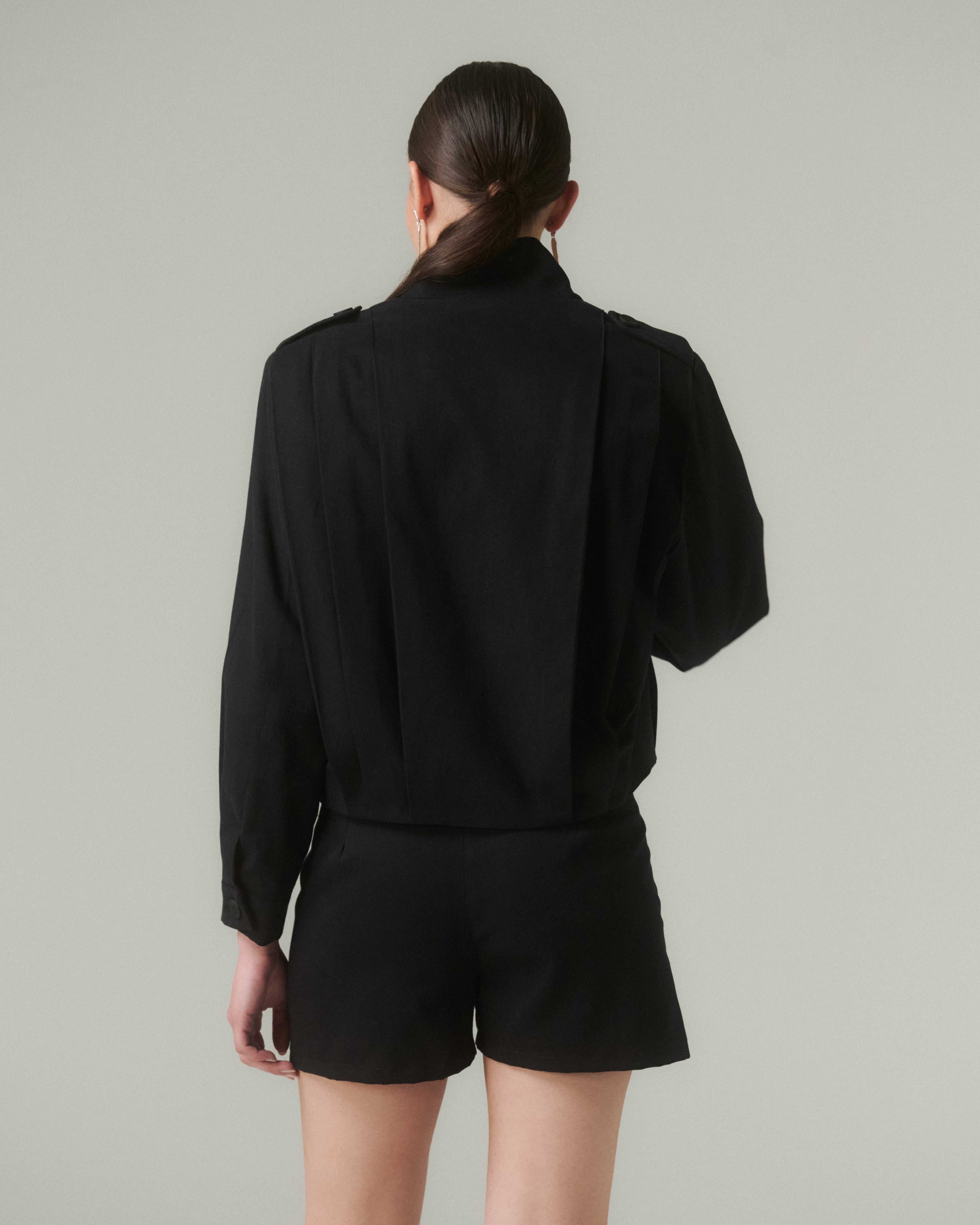 Vista trasera de la Chaqueta Bruna Negro, mostrando su corte recto y detalles en la parte superior.